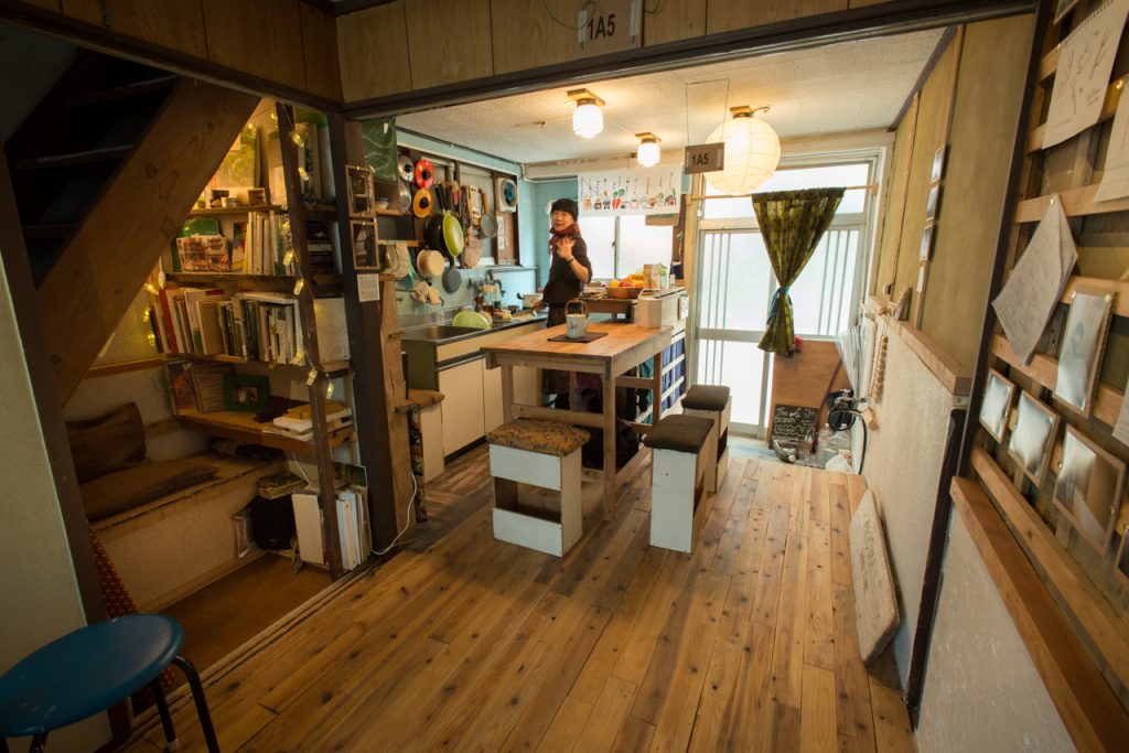 A warm looking home with wood floors and a woman in the kitchen